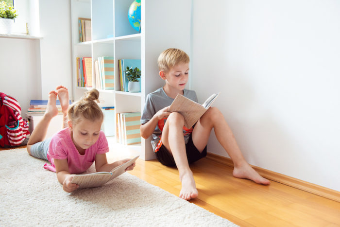 Summer Slide; Two happy children reading books on the floor at the school library