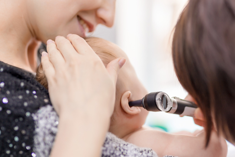 Doctor examining childs ear with otoscope. Mom holding baby with hands. Children healthcare and disease prevention concept; Blog: Ear Infections, What You Need to Know
