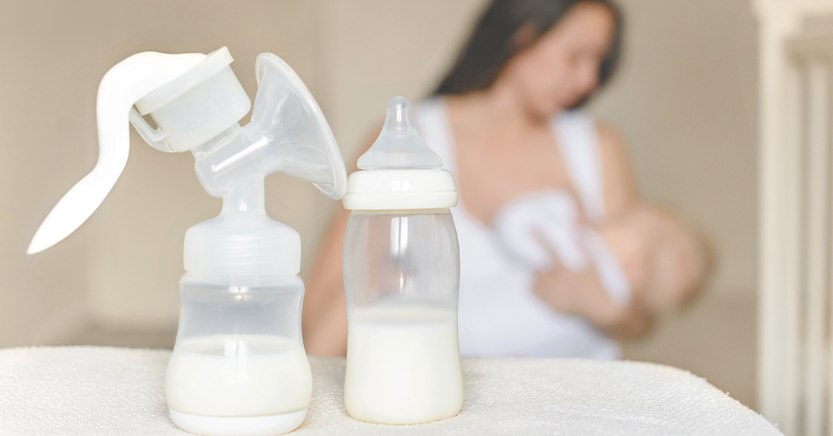 Manual breast pump and bottle with breast milk on the background of mother holding in her hands and breastfeeding baby. Maternity and baby care; blog: Mastitis Symptoms Every Mom Needs to Know