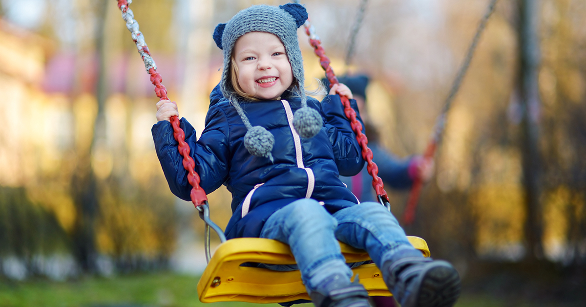 Adorable girl having fun on a swing on beautiful autumn day; blog: winter safety for kids