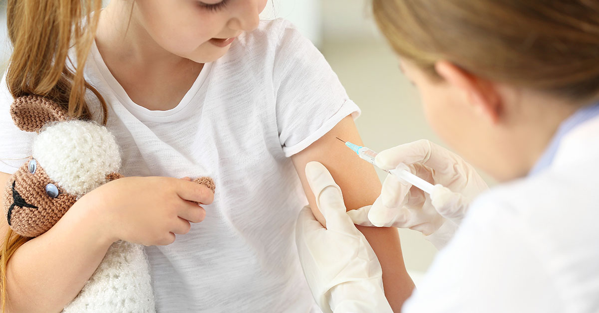 Doctor vaccinating little girl in clinic; blog: vaccine-preventable diseases