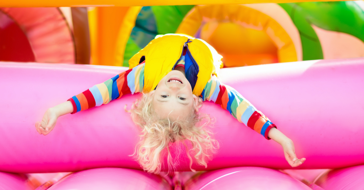 Child jumping on colorful playground trampoline. Kids jump in inflatable bounce castle on kindergarten birthday party Activity and play center for young child. Little boy playing outdoors in summer; blog: 9 Healthy Cold-Weather Activities for Kids