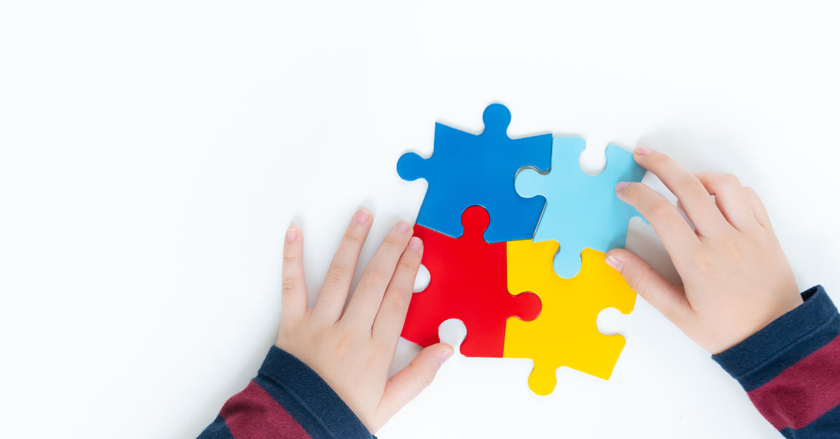 Top view, hands of an autistic child play colorful puzzle which; blog: What are the Early Signs of Autism?