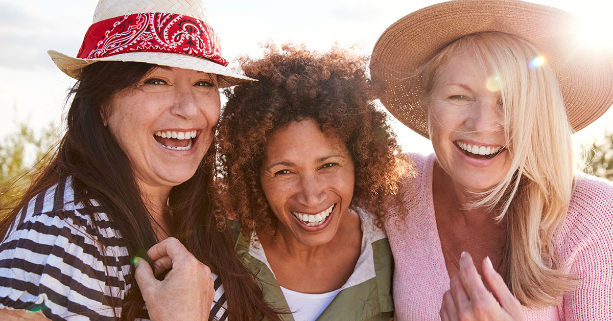 Portrait Of Mature Female Friends Walking Through Field On Camping Vacation; blog: 3 Options for Menopause Management